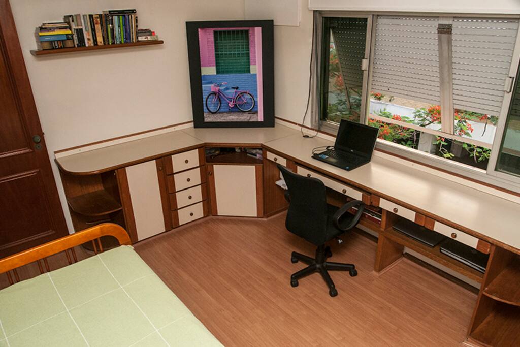 Quarto espaçoso, com bancada e espaço para notebook.
