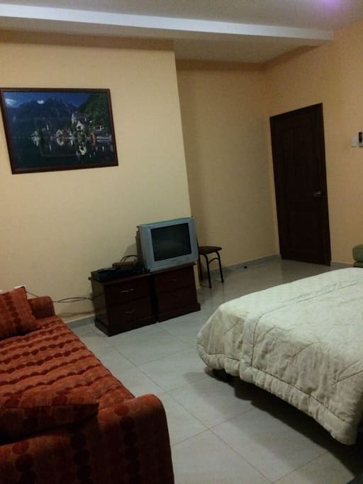 Vista de la puerta de entrada, TV y sofá desde puerta del baño.