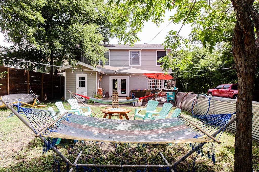 Backyard with seating for 15 plus two hammocks, darts, giant jenga, hula hoops, horseshoes, sandbox, trampoline, and back deck with additional seating for 15 with umbrella and table