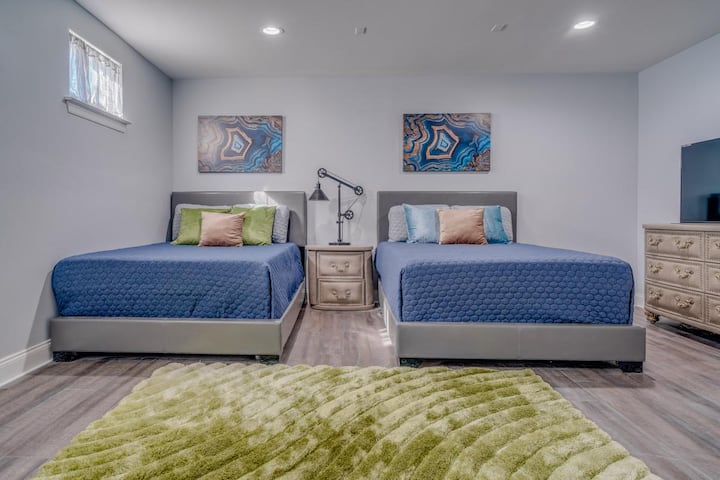 Dormitorio 4. Este dormitorio de invitados está en la planta baja, al mismo nivel que el garaje. Baño completo en suite con ducha a ras del suelo.  Dos camas queen. Armario con vestidor. Cocina pequeña. Vestidor grande, TV de alta definición de 50 pulgadas, Netflix, consola de juegos populares clásica.
