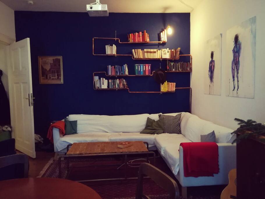the shared living room with a huge sofa, a projector and a second balcony