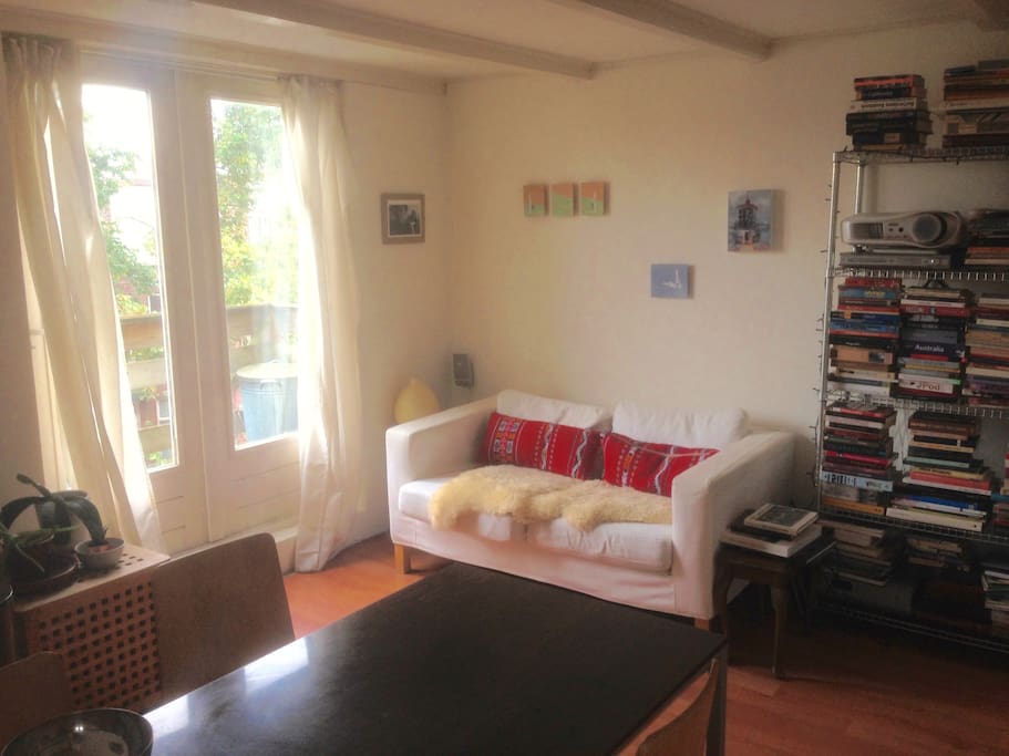 Living room with couch, open kitchen, cupboard bed and access to roof terrace.