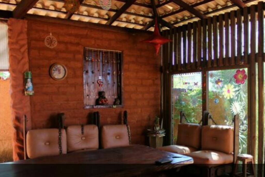 varanda, com mesa para refeições, tv e sofás