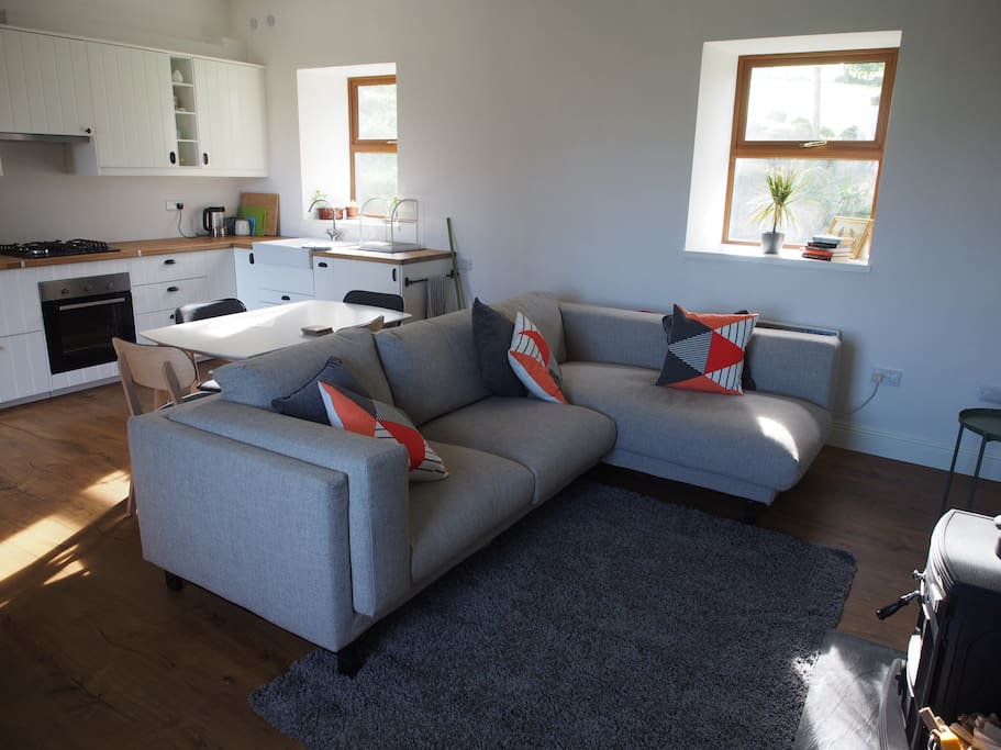 Open plan kitchen leads to living room with sofa and wood burner to keep you warm.