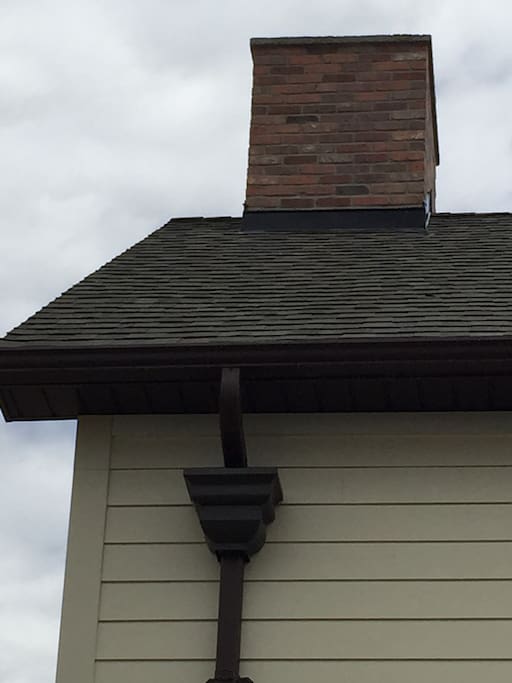Custom masonry on chimney and downspout featuring antique rainwater head.