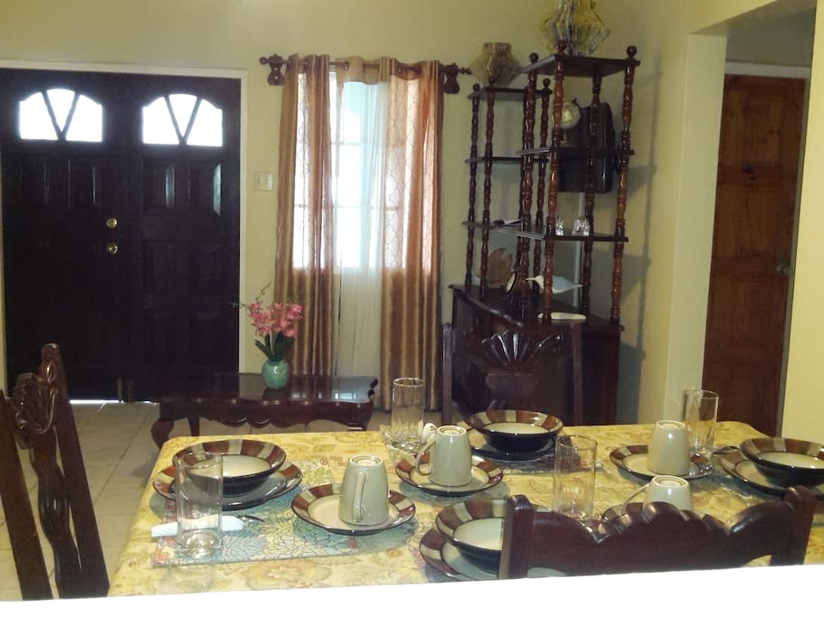 This photograph shows the dining and living spaces. In the background there is a door which leads to one of the private verandahs for this listings.