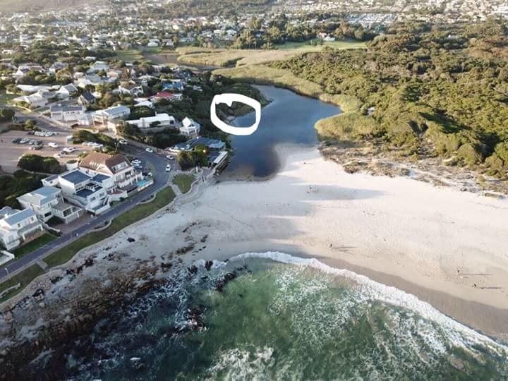 An aerial view captures the serene Onrus lagoon, bordered by sandy beach and lush greenery. The image depicts nearby residential areas and highlights the proximity of the lagoon to the coastline, offering a sense of tranquility in the natural surroundings.