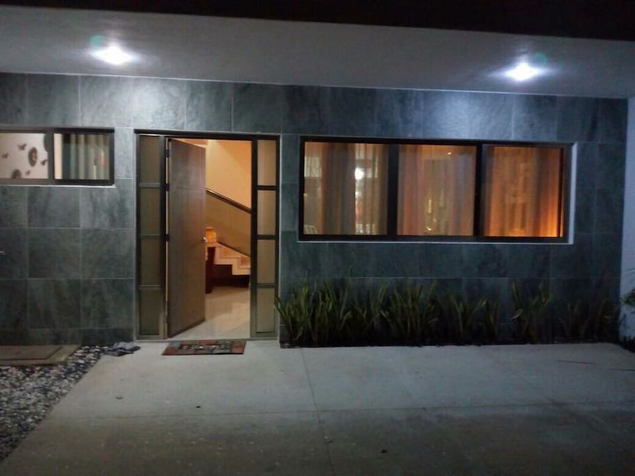 Entrada de la casa con luz y el estacionamiento privado