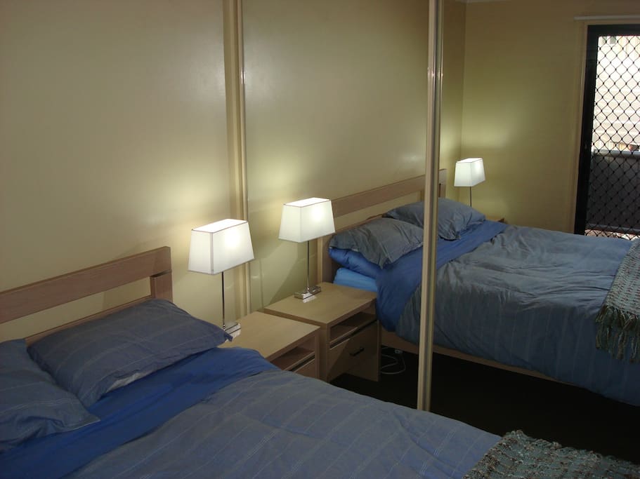 2 bedrooms both with Queen beds with pillows comforted sheets blanket table lamps and mirrored wardrobe. access to balcony