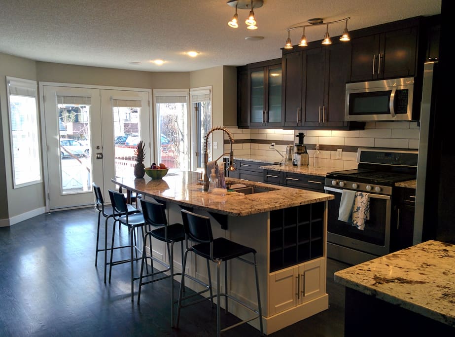 Kitchen features a large granite island, soft-close cabinets, stainless steel appliances, and corner pantry