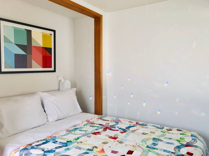 The Rainbow Room is our smallest room with a full bed suitable for one person. It has two windows, art by Mary Iverson and nice light through the day. The bedroom shares a bathroom with the Moon Room.
