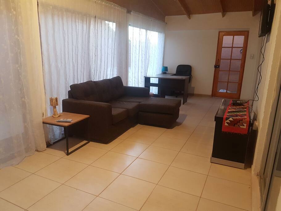sala de estar con tv, escritorio y sillon.