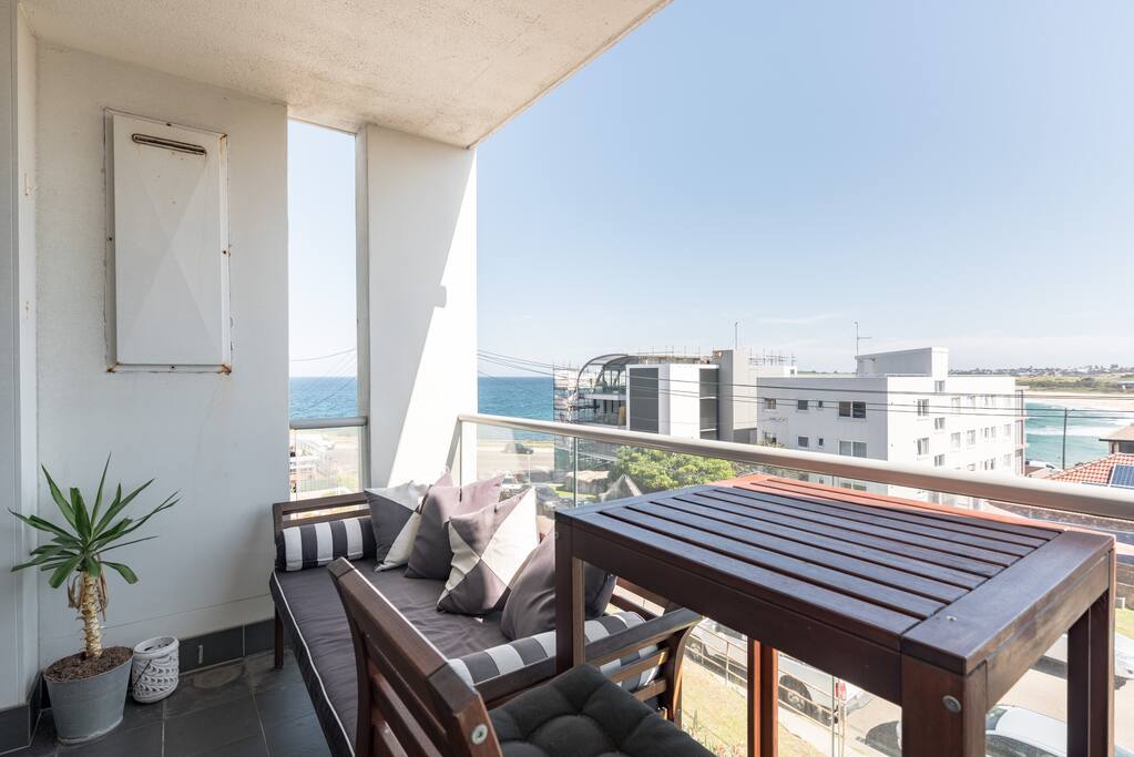 Balcony with day bed and table, overlooking the beach and ocean