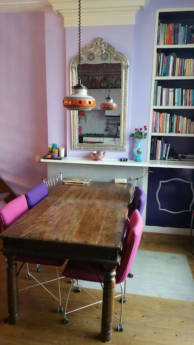 Grote eettafel met fijne stoelen en boekenkast met allerhande boeken