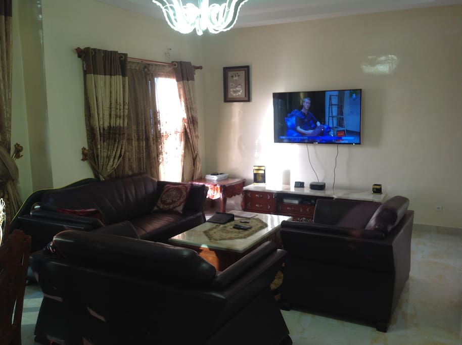 Spacious luxurious living room with real leather furniture, marble flooring, high ceiling and crystal chandeliers.