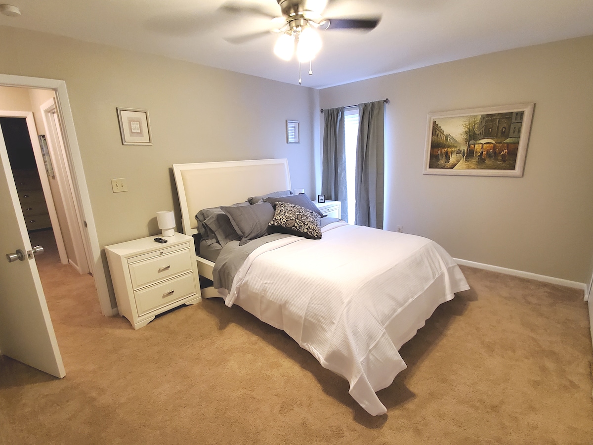 Просторна втора спалня с удобно легло, вентилатор на тавана и тъмни завеси.