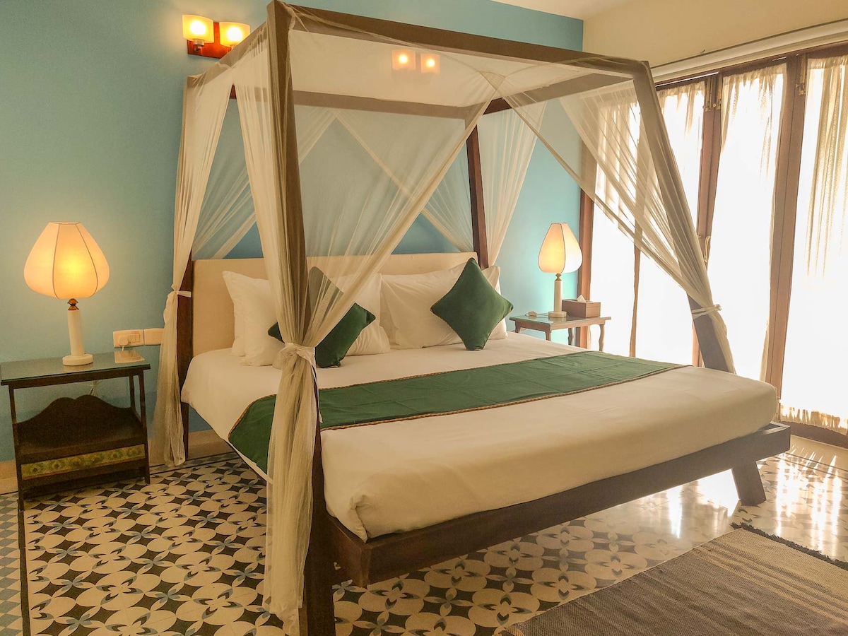 La deuxième chambre de la première villa du premier étage avec un lit à baldaquin en bois dispose d'un petit balcon attenant