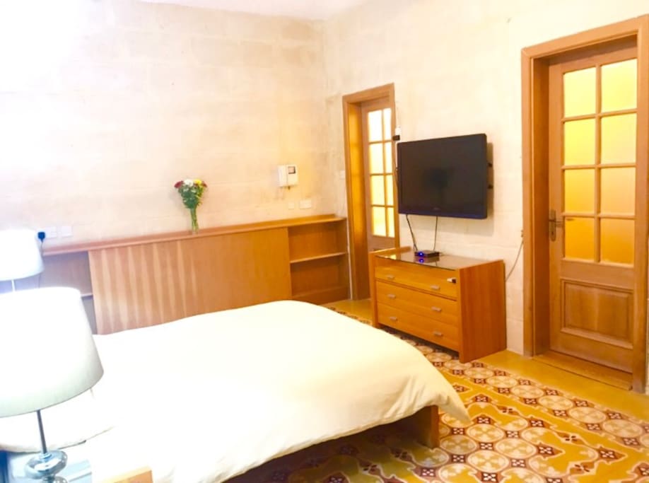 Large double bedroom with ensuite bathroom. traditional Maltese floor tiles and large flatscreen TV