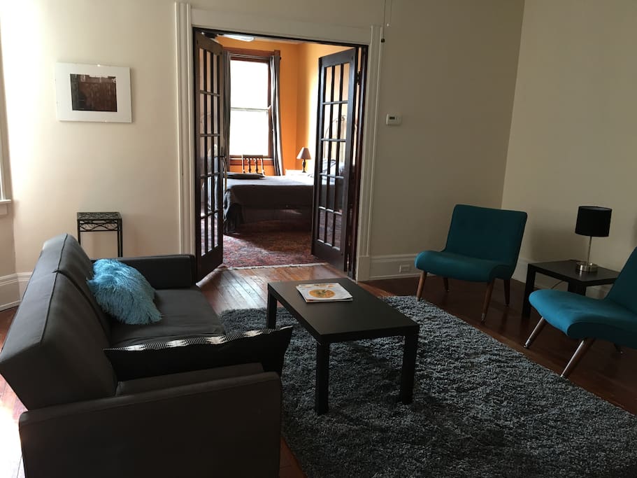 2nd fl living room looking through french doors into bedroom with a full size bed.