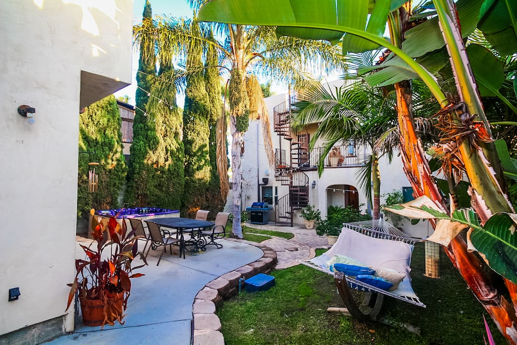 Huge lush backyard with plenty of space and relaxing atmosphere including fire pit, multiple lounges, dining table and a spa