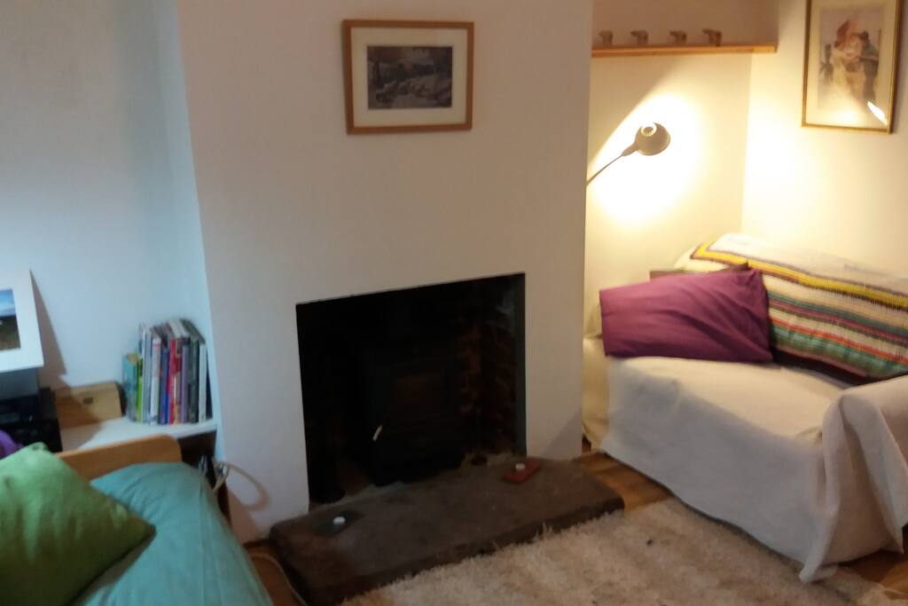 The living room has two sofas, woodstove and a table to sit around