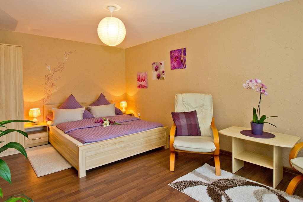 helles Schlafzimmer mit gemütlichem Doppelbett, Kleiderschrank und Blick in den wunderschönen Garten