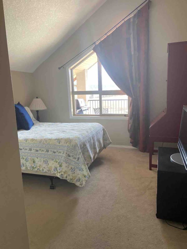 חדר שינה ראשי עם חדר רחצה צמוד, ארון ושולחן כתיבה קטן. 