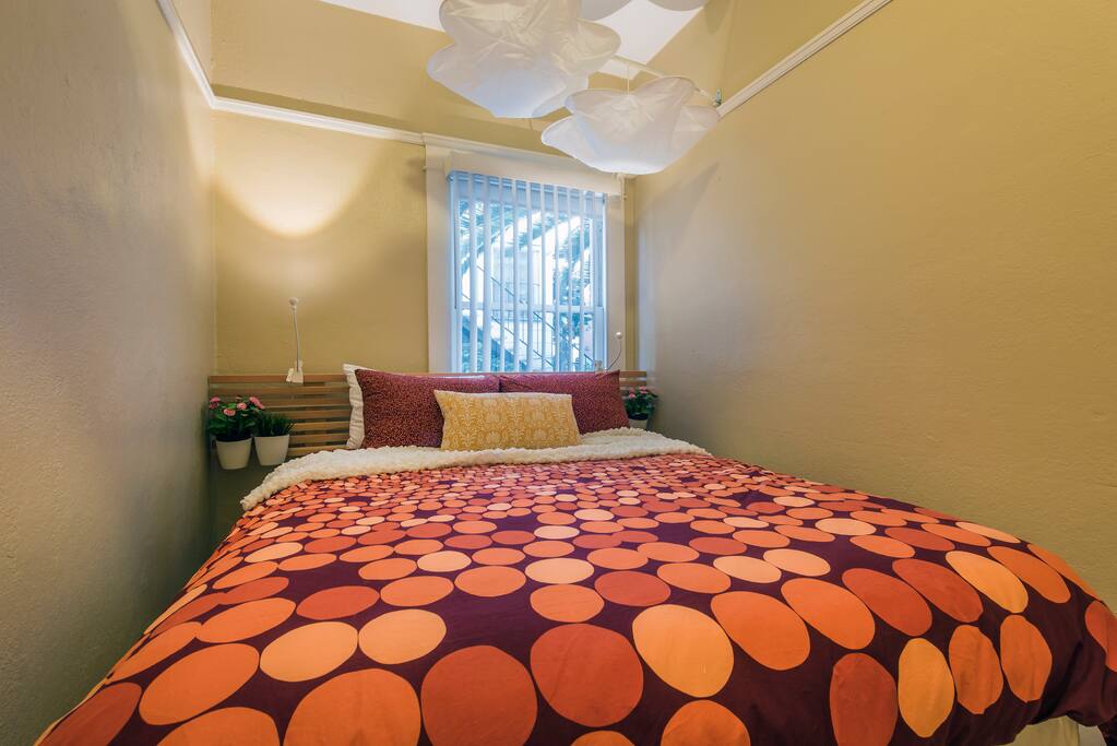 The bedroom features a comfortable queen bed with reading lamps and a dresser filled with extra pillows, linens, and towels.
