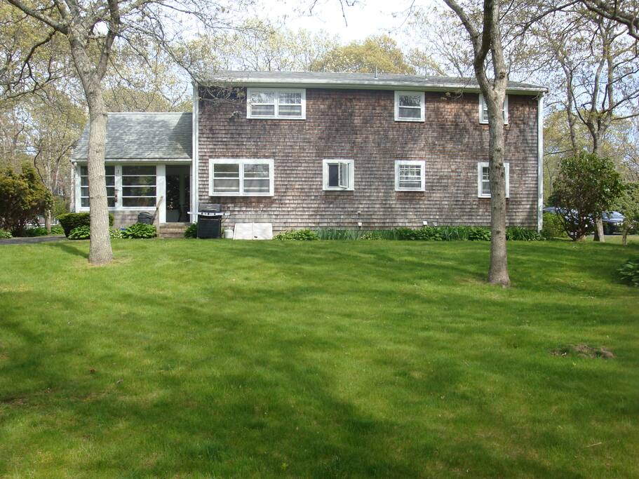 picture from the back yard, showing the gas grill, sun porch, and yard