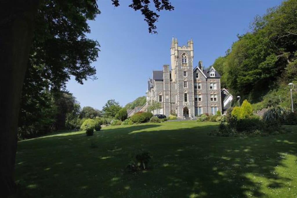 Building exterior showing the spacious grass area, with gated private parking to the left