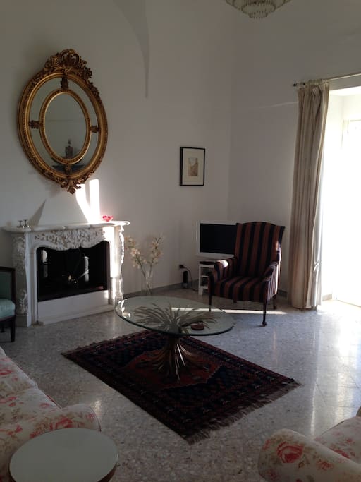 Morning sun in the comfortable, spacious sitting-room with balcony, fireplace, high ceilings and wonderful view.