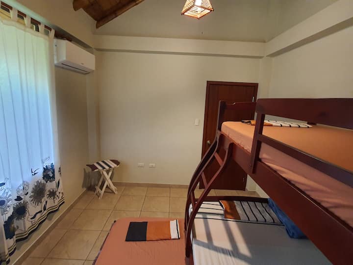 Dormitorio 1 donde descansarás, cuenta con 1 trilera; que tiene una cama en la parte superior y otra en la parte inferior que sale con ruedas; ambas de plaza y media, y una cama de 2 plazas en la mitad. 