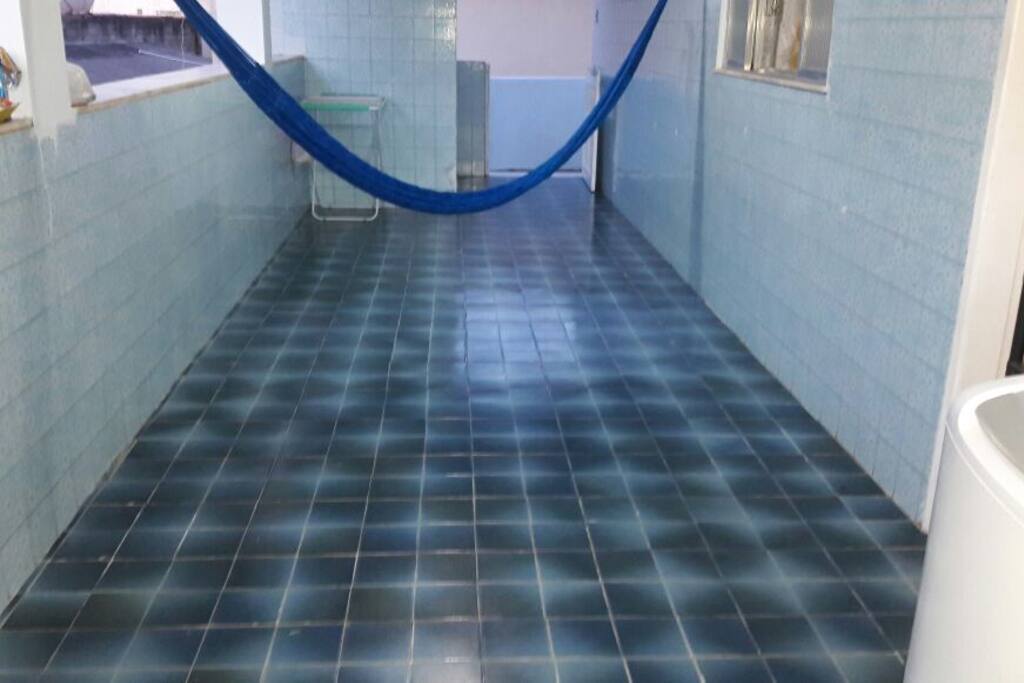 varanda com rede, banheiro externo e área de serviço com máquina de lavar .