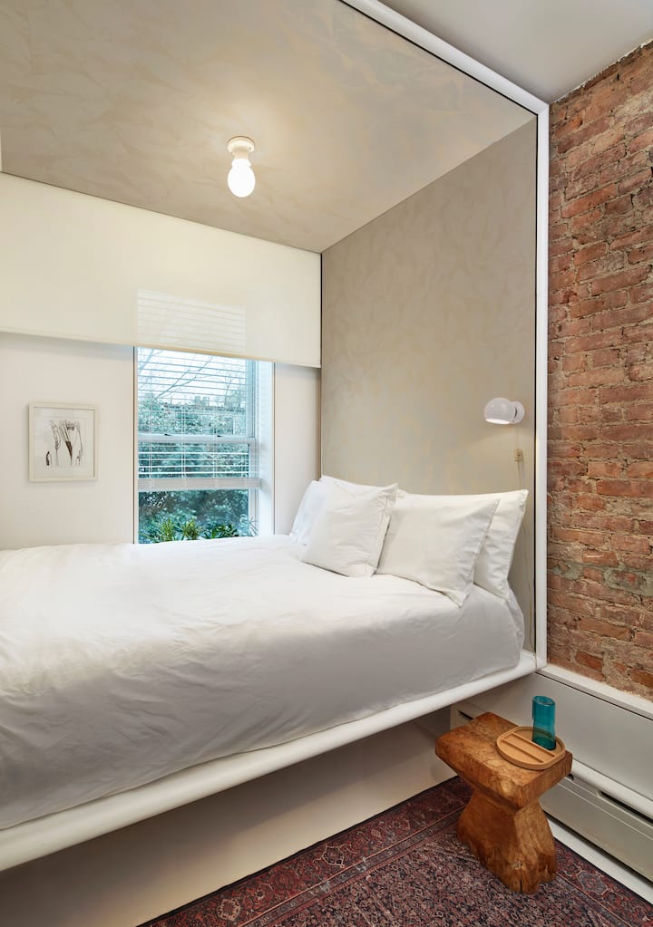 这里是树屋！  它在一张凸起的标准双人床上可睡两人，下方有足够的空间放置行李箱。  有一个梯子，方便出入。  窗户俯瞰花园，树木全年郁郁葱葱，绿意盎然。