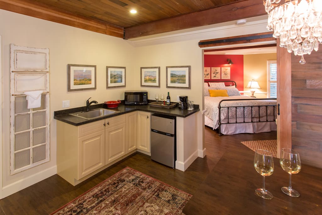 Kitchenette featuring a sink, microwave, and refrigerator with freezer. Wine glasses, ice bucket, and coffee maker with mugs are also included.