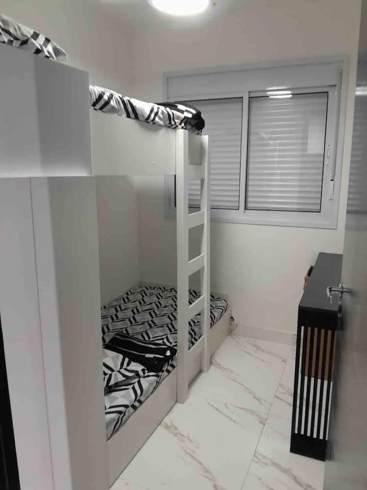 ห้องพักพร้อมเตียงสองชั้นและที่นอนเอ็มม่าเดี่ยว 2 อันพร้อมโต๊ะสำนักงานและตู้เสื้อผ้าขนาดเล็ก 