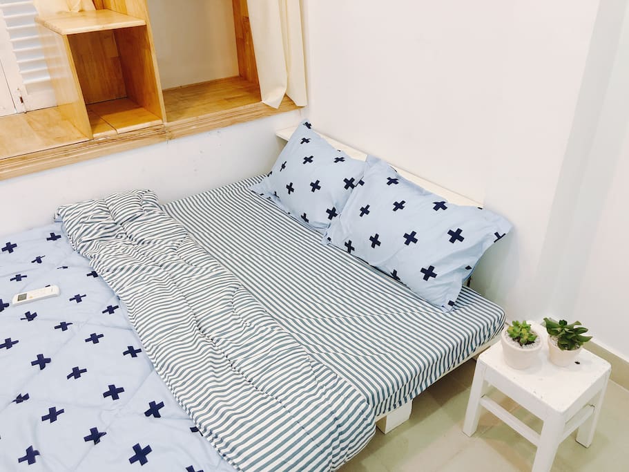 A double sized bed in a cozy private room with a bedside table