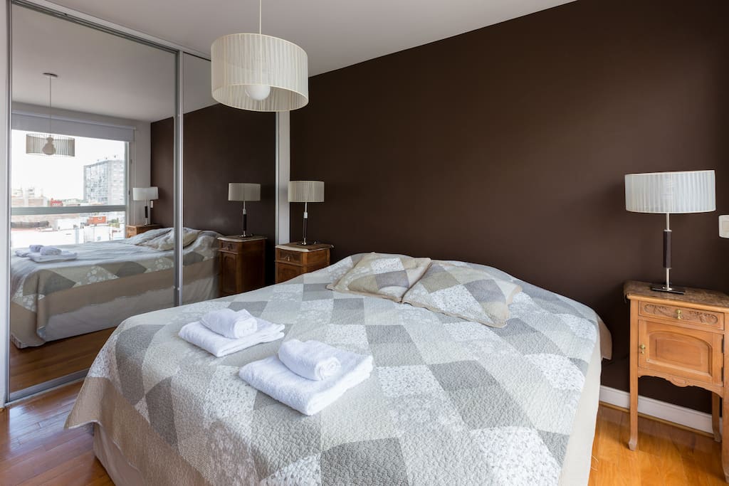 The master bedroom has a king-sized bed, floor-to-ceiling mirrored closets and design bedside lamps and tables