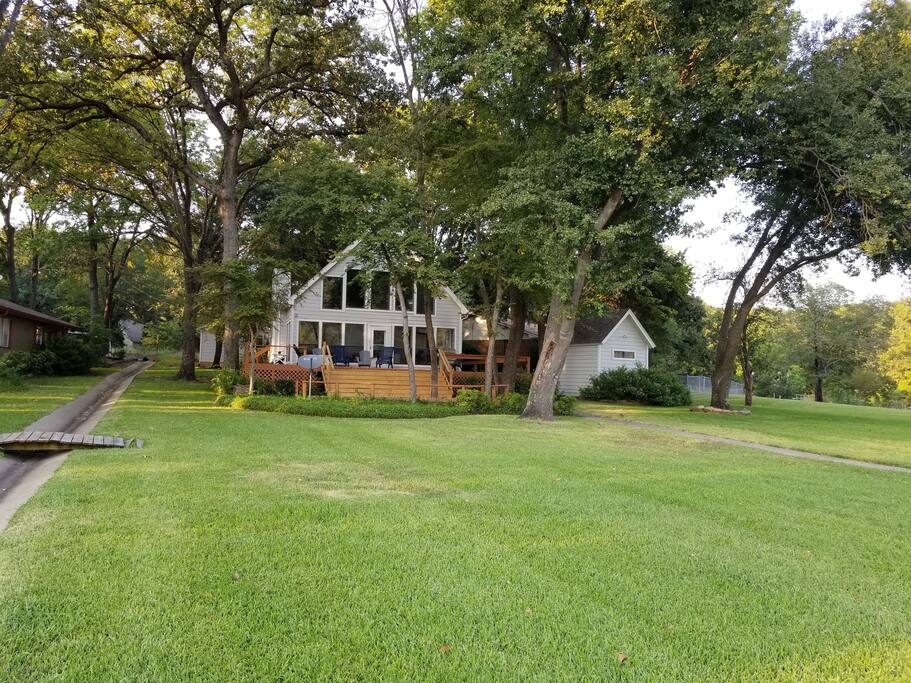 Open, two-story deck facing lake with large yard for volleyball or throwing the ball.