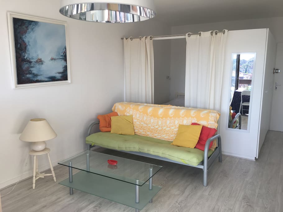 Le canapé du salon et derrière la chambre en alcôve
