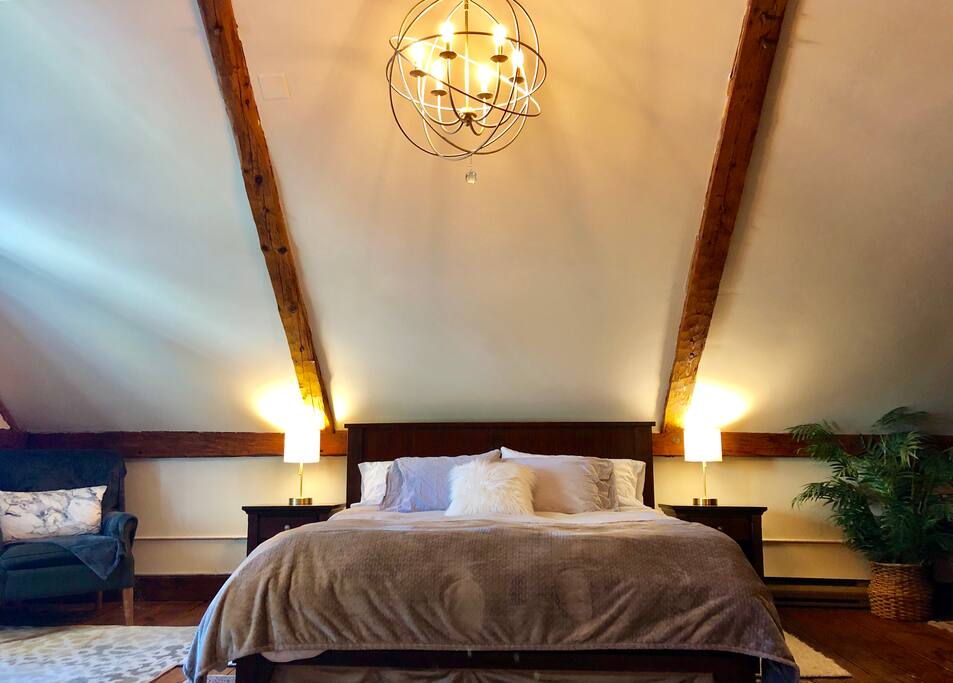 In the sleeping loft, there is a king bed with a dimmable chandelier and reading lamps. A historic and romantic spot. The floors are very rustic and uneven because they have shifted in the last 250 years, the bed is even though!