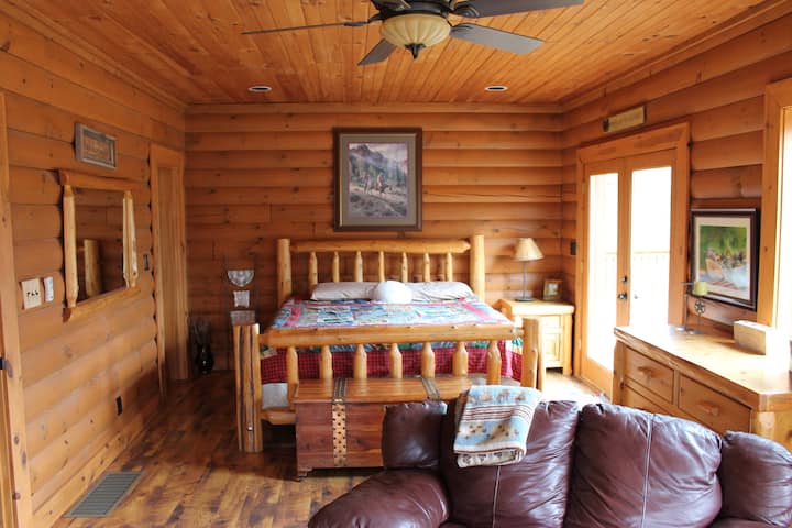 Suite parentale avec lit king size en rondins pelé à la main, bibliothèque et coin salon