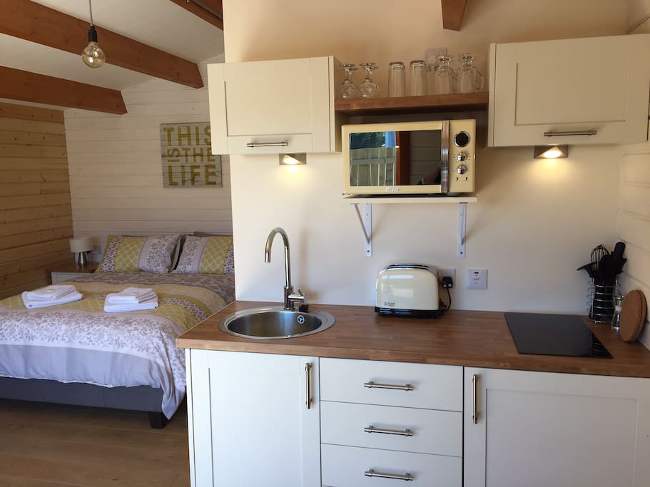 Kitchen with fridge/freezer, dual induction hob, microwave oven.