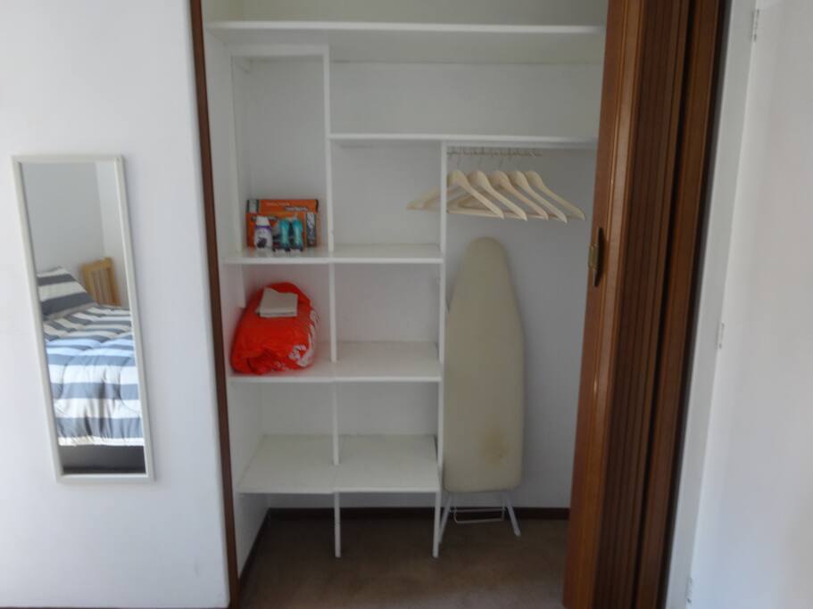 guardarropa con ganchos, plancha, mueble para planchar, toallas de baño limpias