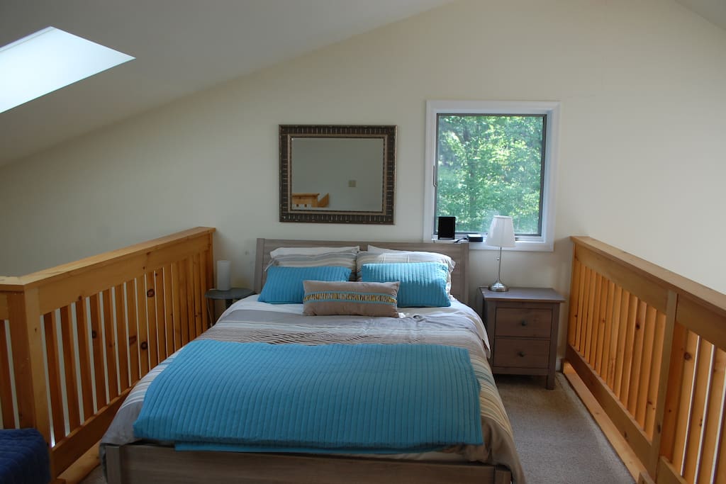 Queen bed in loft with sky light.