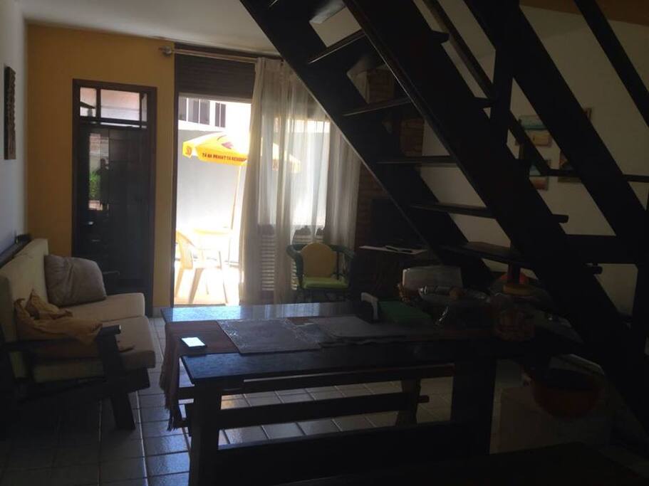 SALA DE ESTAR, MESA PARA JANTAR E ATRAS UM ESPAÇO COM LAVANDERIA E VARAL