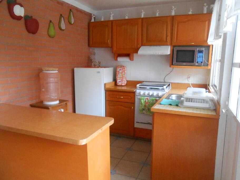 Cocina con refrigerador,estufa, licuadora, sandwichera y horno de microondas.