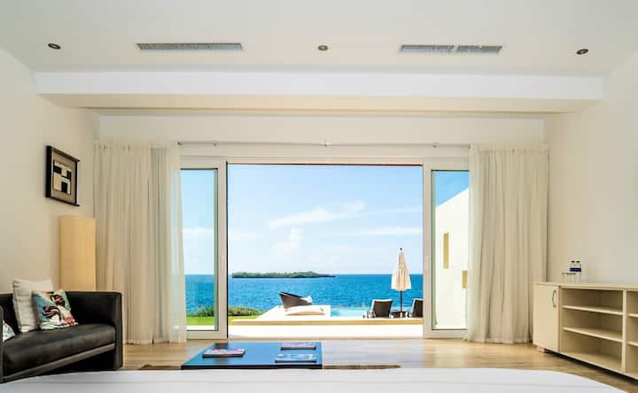 Dormitorio principal de lujo: cama tamaño king, baño privado con ducha/bañera, aire acondicionado, TV, caja fuerte y acceso directo a la terraza. 