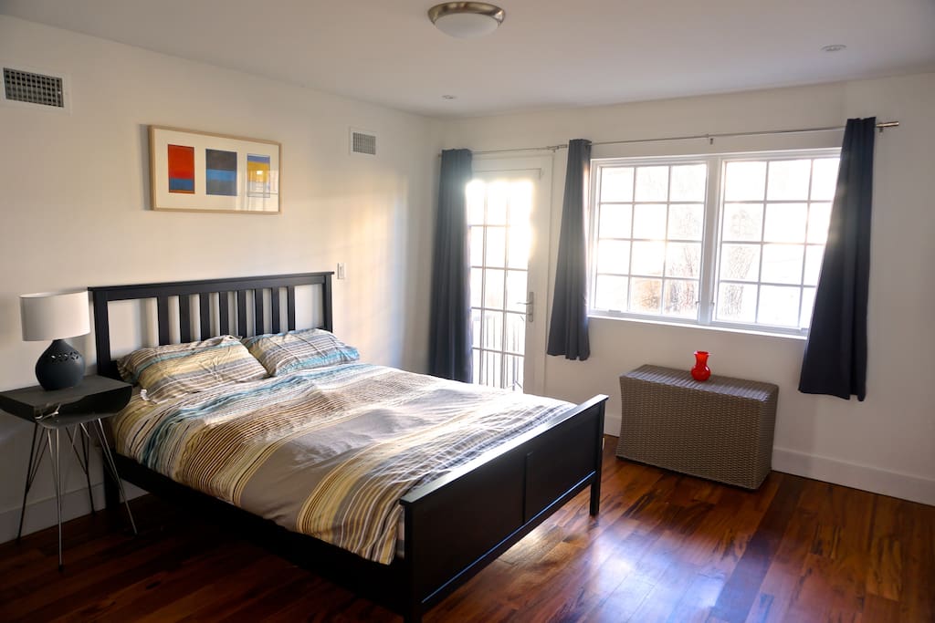 Bedroom with access to private backyard, en suite bathroom and queen bed.
