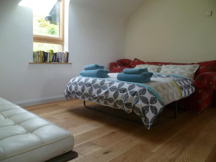 บนชั้นลอยมองลงไปที่พื้นที่นั่งเล่นเป็นพื้นที่สวยงามที่มีเตียงโซฟาแบบดึงลงมานอนได้ 2 คน